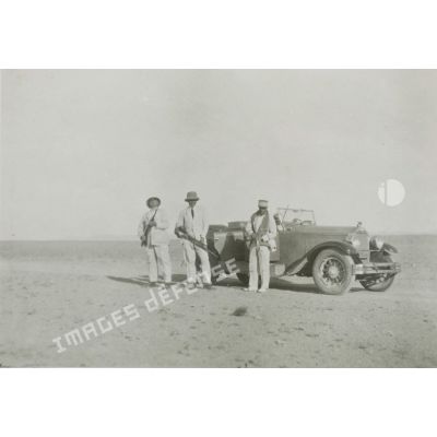 [Portrait de chasseurs près d'une automobile dans un désert].
