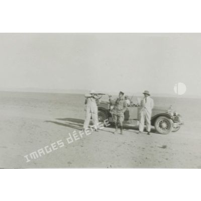 [Portrait de chasseurs près d'une automobile dans un désert].