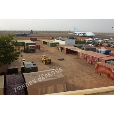 Derrière une zone de regroupement logistique, un avion-cargo de transport Antonov 124-100 ukrainien stationne sur une piste de l'aéroport de Bamako, pendant le roulage d'un Hercules C-130 de l'armée nigériane.