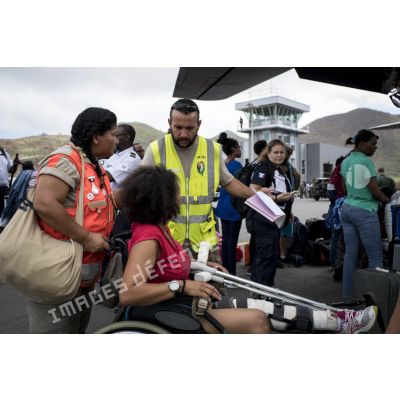 Un personnel de la base aérienne 367 de Cayenne prend en charge une personne à mobilité réduite pour son évacuation à bord d'un avion Casa Cn-235 à Grande Case sur l'île de Saint-Martin, aux Antilles.
