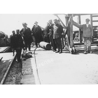 [Jules-Louis Breton posant au milieu d'une délégation venue inspecter du matériel d'artillerie sur un site naval.]