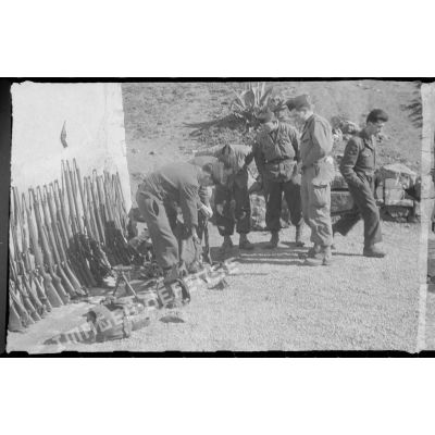 Dans une cour, des soldats déballent le matériel saisi au cours d'une opération. [légende d'origine]