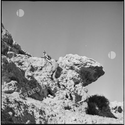 Deux soldats escaladent un rocher. [légende d'origine]