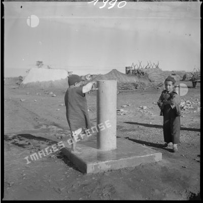 Aménagement de l'eau dans le secteur de Tamesna sous le commandement du capitaine Vinck. Deux jeunes garçons jouent autour du point d'eau. [légende d'origine]