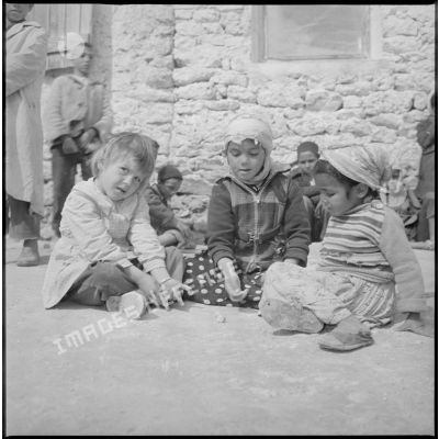 Tournée de secteur près de Tamesna et de Fenouane. Portraits de jeunes enfants qui jouent. Ils sont assis dans une cour. [légende d'origine]