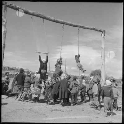 Tournée de secteur près de Tamesna et de Fenouane. Des enfants jouent et montent à la corde sur une aire de jeux. [légende d'origine]
