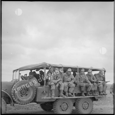 Portrait de groupe de soldats assis, dos à dos, dans un camion de transport de troupes. [légende d'origine]