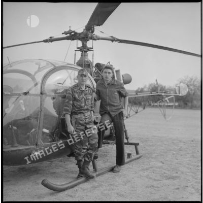 Arthur Smet et un homme posent devant un hélicoptère. [légende d'origine]
