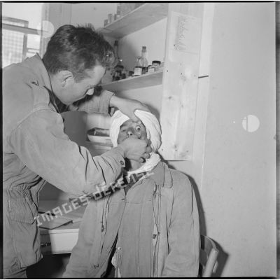 Tournée de secteur du colonel Alexandre. Un médecin militaire procède à une auscultation oculaire sur un patient. [légende d'origine]