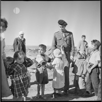 [Un soldat et des enfants du village marchent main dans la main.]