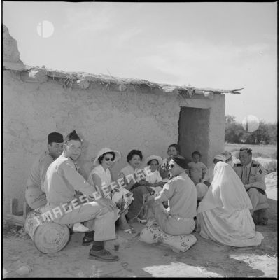 A l'occasion de la visite d'un village, des officiers boivent le thé devant une maison. [légende d'origine]