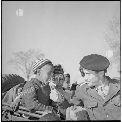 Un soldat allume la cigarette d'un jeune garçon du village. [légende d'origine]