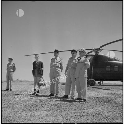 L'Amiral Mouton et son fils devant un hélicoptère. Le colonel Brunet se tient également aux côtés de l'Amiral en visite au Camp des chasseurs. [légende d'origine]