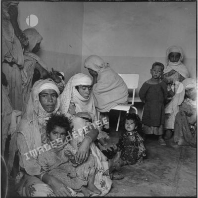 Portrait d'un groupe de femmes et d'enfants assis dans une salle d'attente. [légende d'origine]