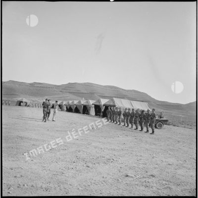 Un officier salue un groupe de soldats au garde-à-vous devant leurs tentes au cantonnement du Kreider. [légende d'origine]