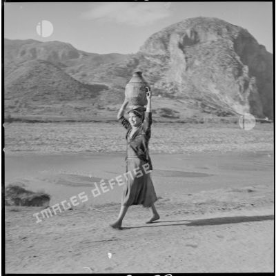 [Femme transportant l'eau puisée du bas-Rhummel (ou Oued-el-Kébir).]
