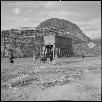 [Femmes kabyles marchant le long d'une structure en construction.]