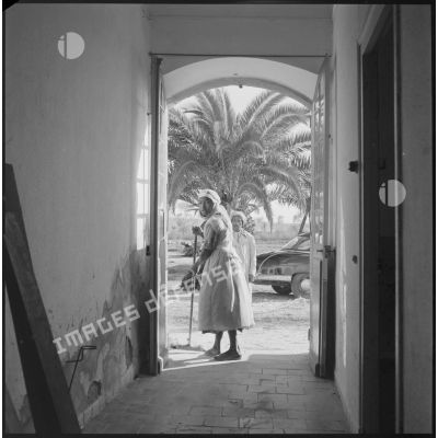 [Femme de ménage algérienne balayant un pas-de-porte au cantonnement de la ferme Carafon du commando Georges.]