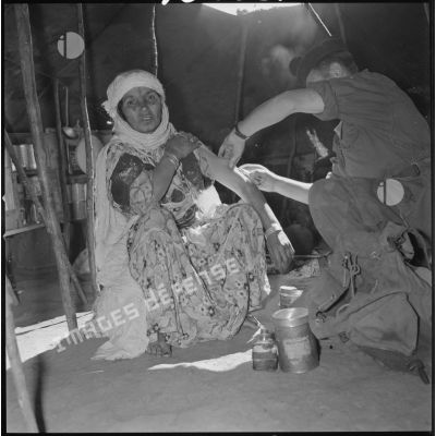 [Soldat vaccinant une femme dans une tente traditionnelle de nomades à AÏn Skhouna.]