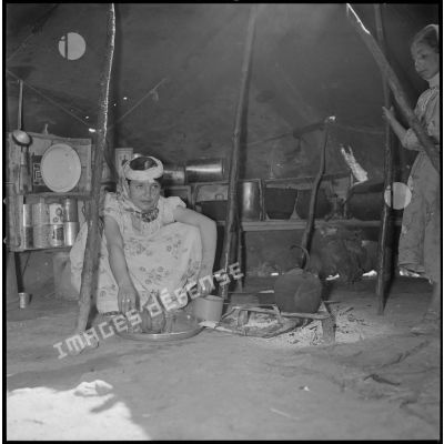 [Jeune femme nomade préparant le thé dans une tente traditionnelle à Aïn Skhouna.]