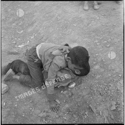 [Enfants jouant au sol dans un camp de regroupement de nomades à Aïn Skhouna.]