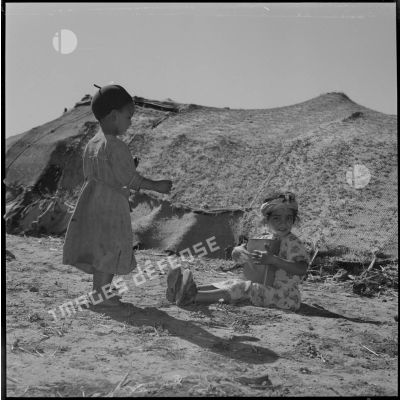 [Petites filles jouant des percussions et dansant dans un camp de regroupement de nomades à Aïn Skhouna.]