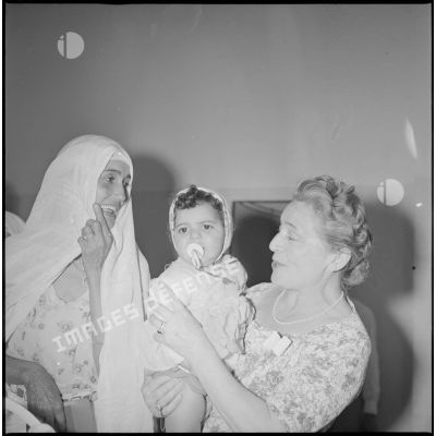 [Portrait de l'épouse du préfet de Saïda tenant un enfant algérien dans ses bras.]