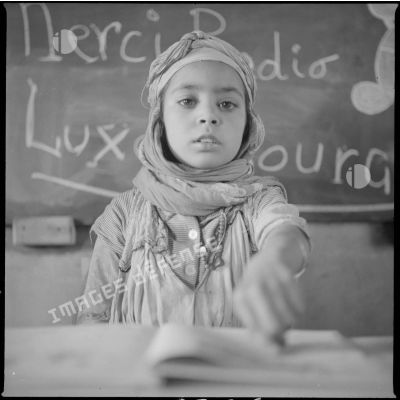 [Poste de Tamesna, région de Saïda. Portrait d'une enfant devant un tableau portant l'inscription "Merci Radio Luxembourg".]