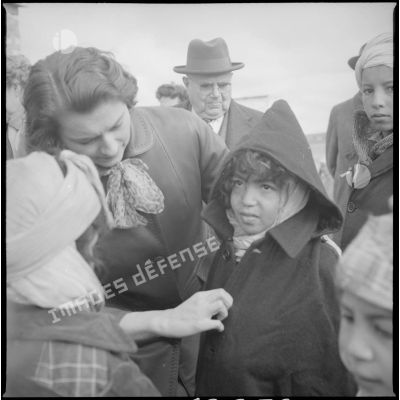 [Poste de Tamesna, région de Saïda. Femme aidant une enfant à mettre un manteau donné à l'occasion d'une action caritative initiée par des Luxembourgeois.]