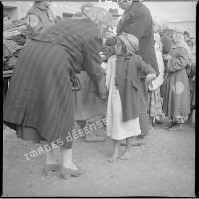 [Poste de Tamesna, région de Saïda. Femme aidant une enfant à mettre un manteau donné à l'occasion d'une action caritative initiée par des Luxembourgeois.]