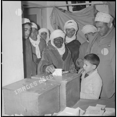[Un Algérien dépose son bulletin de vote dans une urne à la mairie de Wagram.]