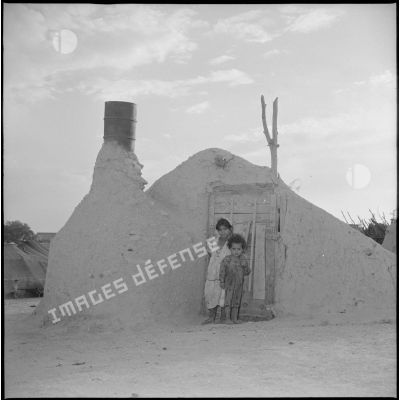 [Jeunes filles posant devant un gourbi du centre de regroupement d'Aïn Sekhouna.]