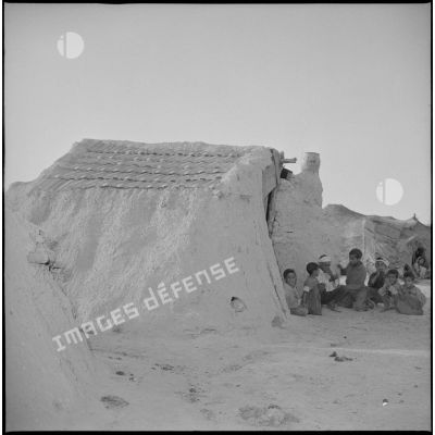[Enfants algériens devant un gourbi du centre de regroupement d'Aïn Sekhouna.]