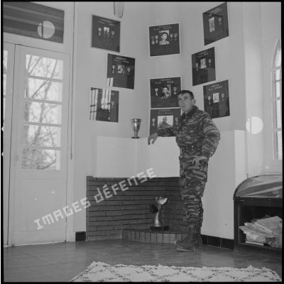 [Portrait d'un sergent devant le mur d'honneur des Cobra à la ferme Rouge.]