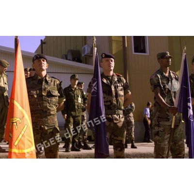 Trois porte-drapeaux de la cérémonie : drapeau du CINC-SOUTH (commandement en chef des forces alliées d'Europe du sud) en rouge, porté par un soldat espagnol, et drapeaux de l' OTAN et de la KFOR.