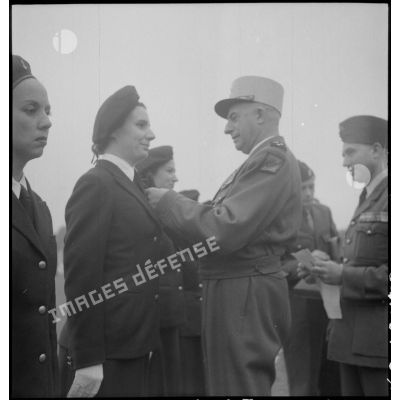 Le général de Linarès décore une femme appartenent à l'état-major du 2e bureau FTNV (forces terrestres du Nord-Vietnam), lors de la prise d'armes du PFAT(personnel féminin de l'armée de Terre) au stade Mangin.