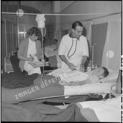 Un médecin et une infirmère examinent un homme à l'hôpital militaire Lanessan.