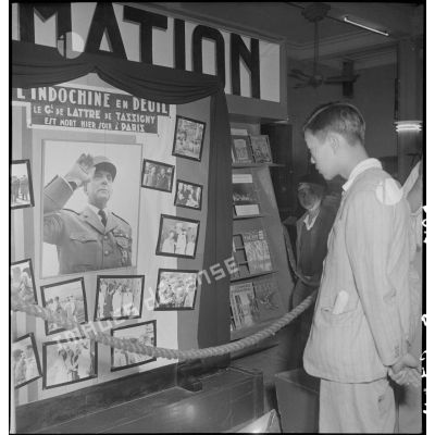 Jeune homme devant un panneau d'information annonçant la mort du maréchal de Lattre de Tassigny dans un hall du Service d'information.