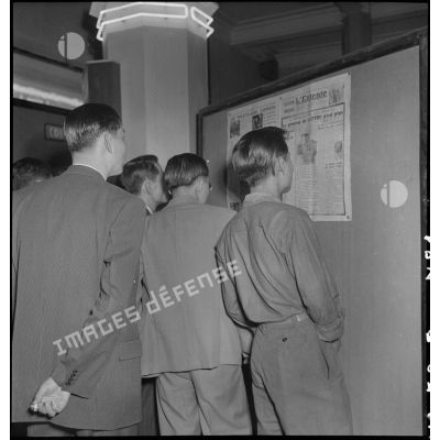 Groupe de civils devant un panneau d'information annonçant la mort du maréchal de Lattre de Tassigny dans un hall du Service d'information.