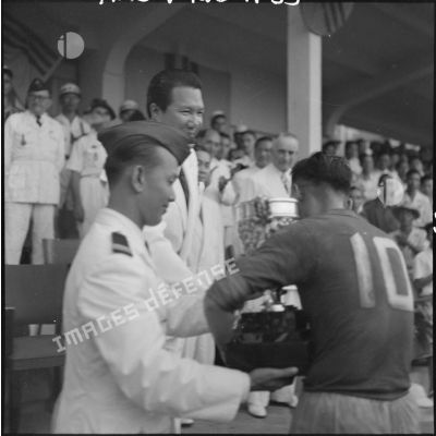 A l'issue du match de la finale de la coupe de l'Unité, M. Bao Daï remet une coupe à un footballeur.
