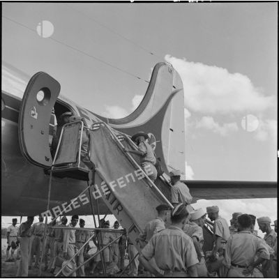Deux soldats des troupes coloniales embarquent à bord d'un avions pour un pèlerinage à la Mecque.	