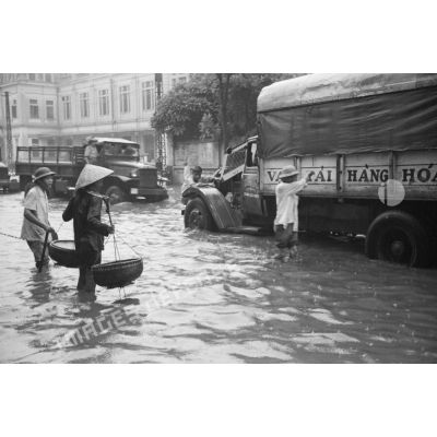 Un camion militaire et un camion de transport dans une rue inondée par les pluies.