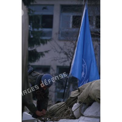 Un soldat russe hisse le drapeau de l'ONU sur son mât à Sarajevo.