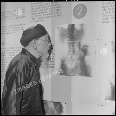 Vieil homme ragardant une radiographie sur un panneau d'une exposition scientifique ayant lieu à l'université d'Hanoï.	