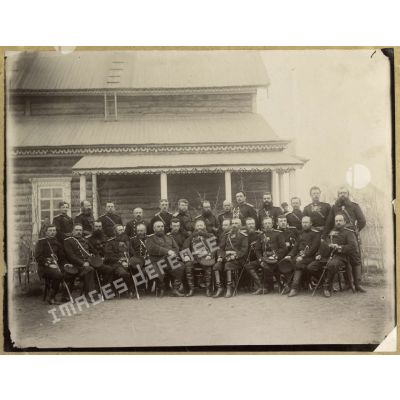 [Portrait de groupe d'officiers russes assis devant une maison traditionnelle en bois].