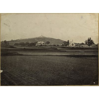 [Chine, 1887-1891. Vue d'une plaine avec des bâtiments de style colonial dont une église. A l'arrière-plan, sur une colline, un ouvrage fortifié].
