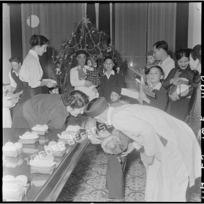 La fille et l'épouse du général Cogny, commandant en chef des FTNV (forces terrestres du Nord-Vietnam), remettent des cadeaux à des enfants vietnamiens lors d'une fête de Noël.