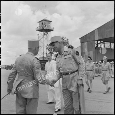 Le général Navarre, commandant en chef en Indochine, est accueilli par le général Cogny, commandant en chef des FTNV (forces terrestres du Nord-Vietnam), avec qui il échange des salutations sur l'aérodrome de Bach Mai.
