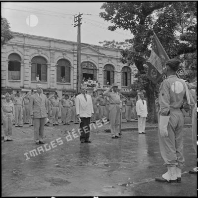 M. Gautier, M. Dejean, le général Cogny, et M. Nguyen Huu Tri saluent les drapeaux.
