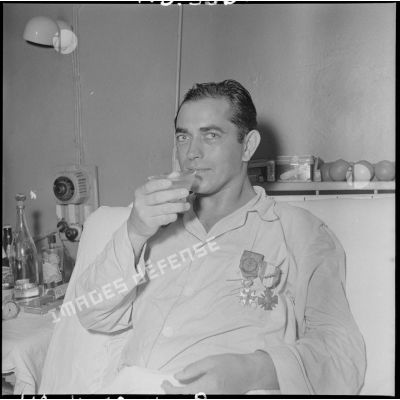 L'adjudant-chef Bartier boit un verre après avoir été décoré de la Légion d'honneur et de la Croix de guerre des TOE par le général Dechaux à l'hôpital Lanessan.